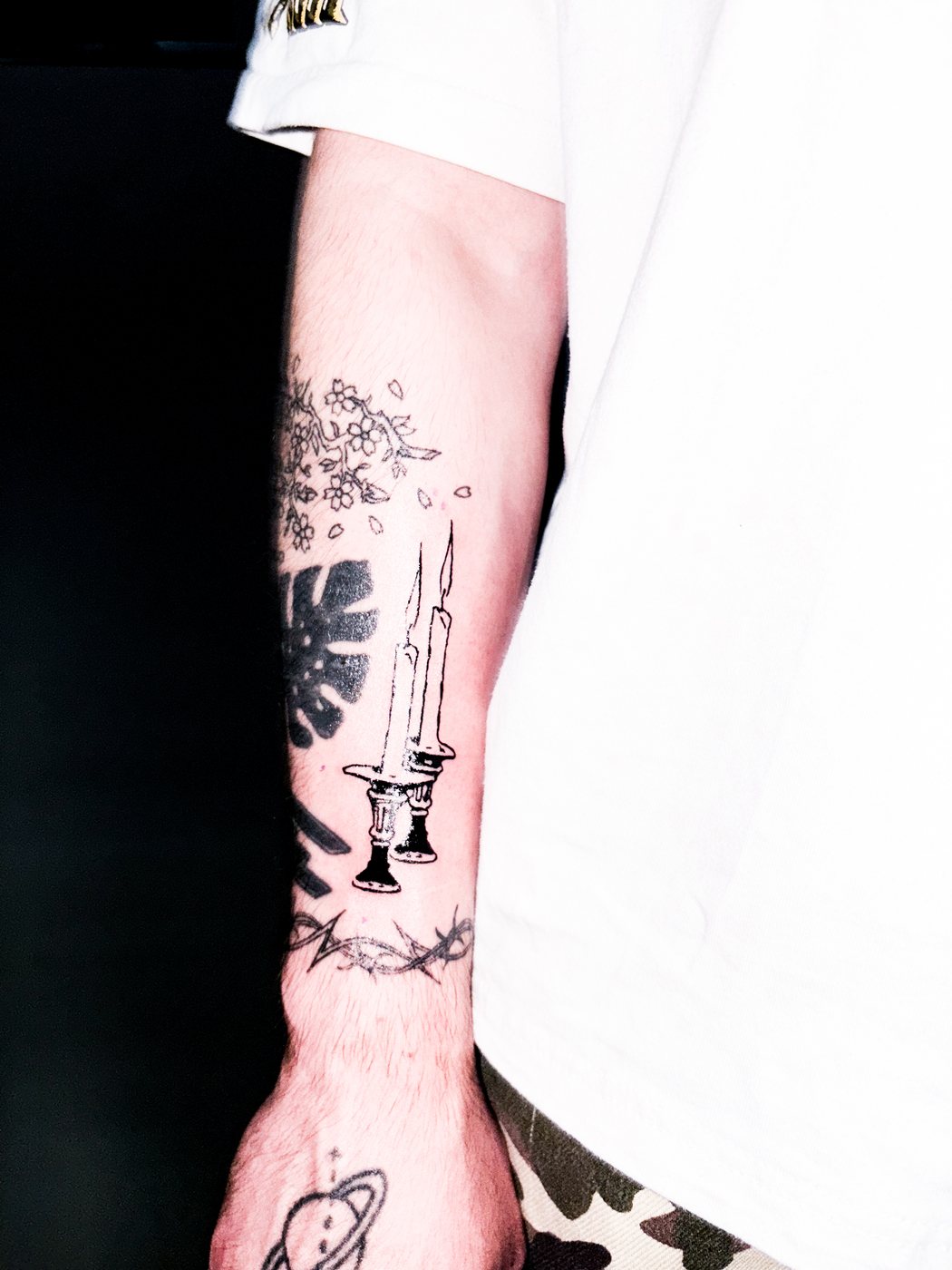 fine line candles, monstera leaf and planet on a forearm
